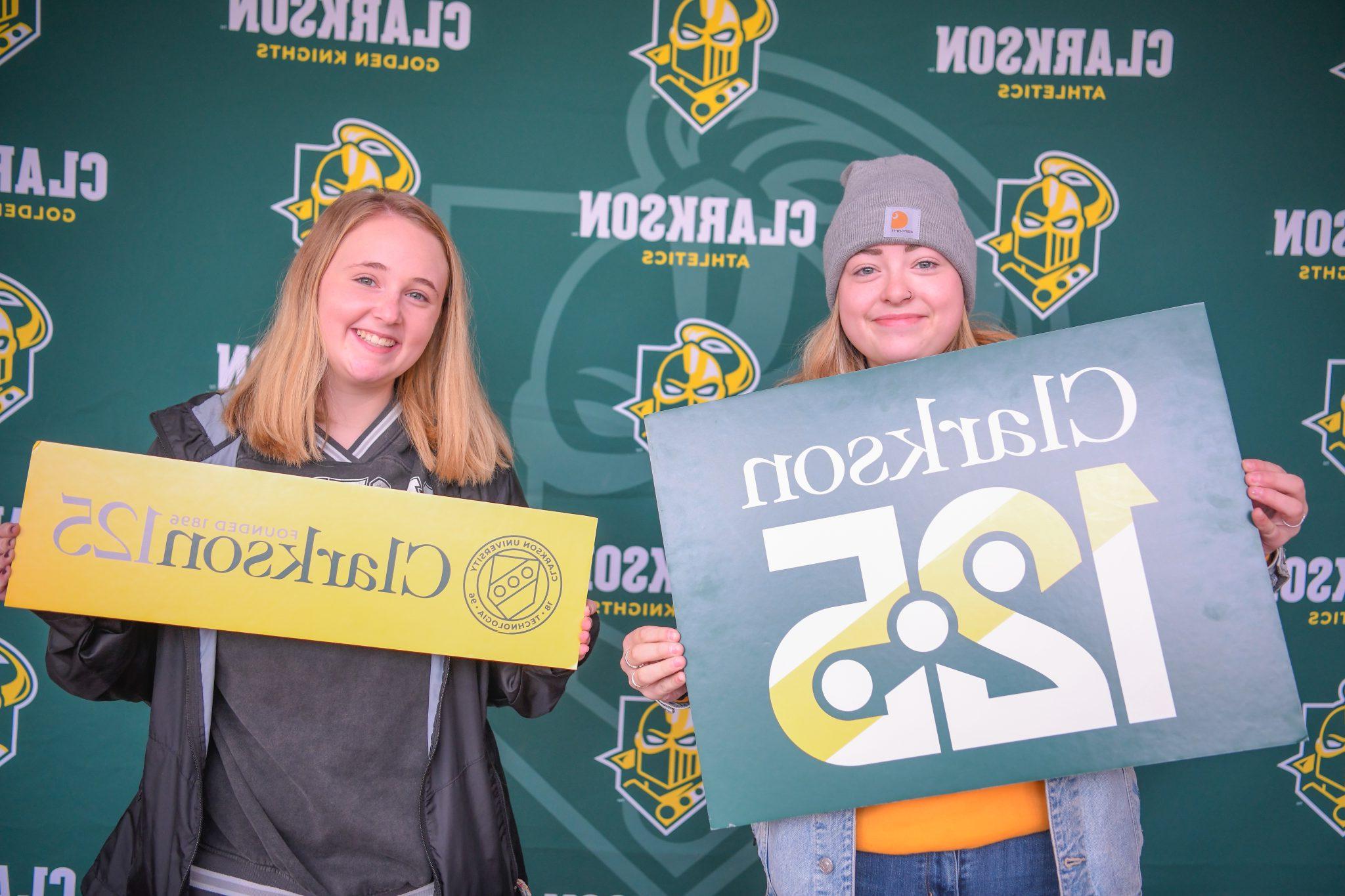 Two students holding up Clarkson 125 anniversary signs. 